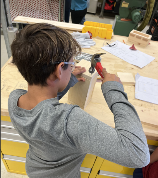 One student with a hammer working on a woodshop project