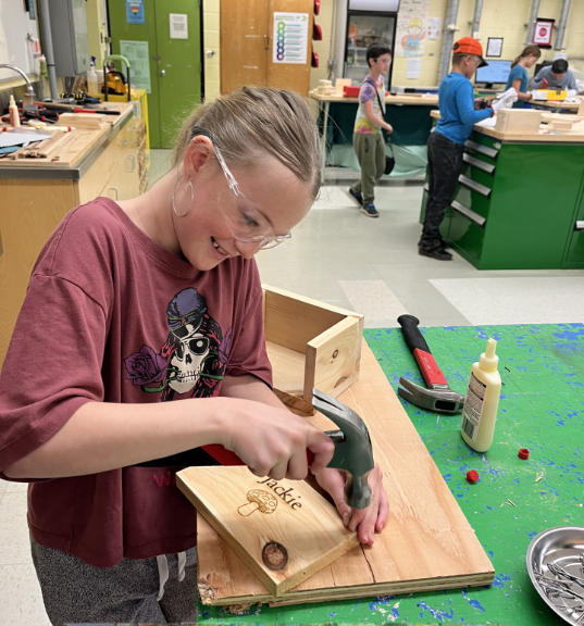 A student with safety goggles working on a woodshop project