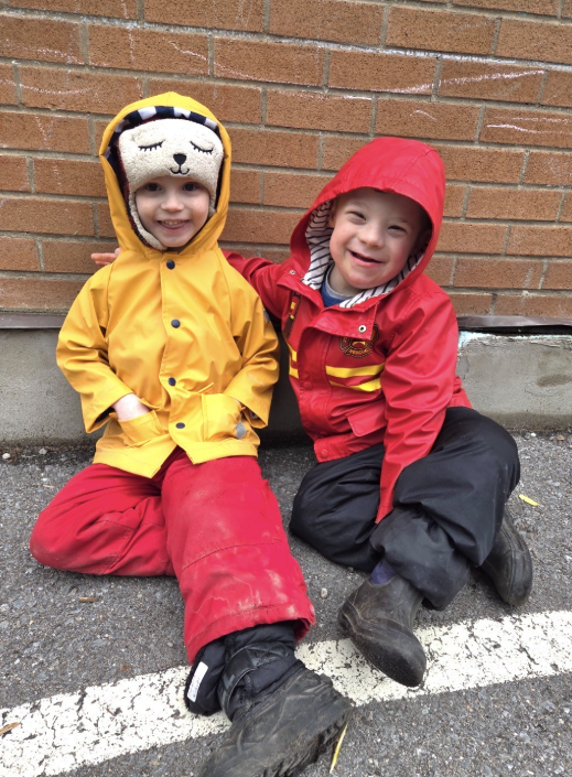 Two students sitting outside in rain coats